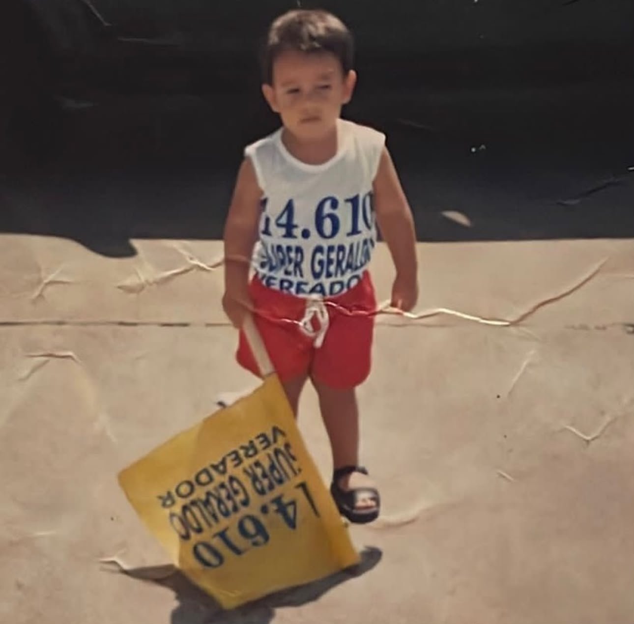 Matheus de Geraldinho ainda criança, ao lado do material de campanha do avô, Super Geraldo